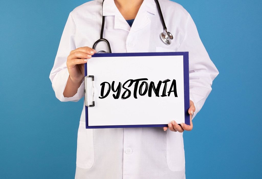Arzt hält einen Schild mit der Schrift Dystonia im blauen Hintergrund