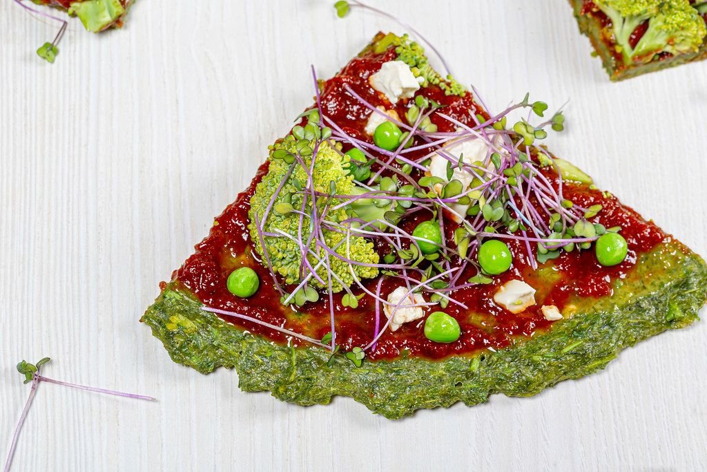 Close-up vegetarische Pizza mit Gemüse und Mini-Brokkoli auf einem weißen Hintergrund