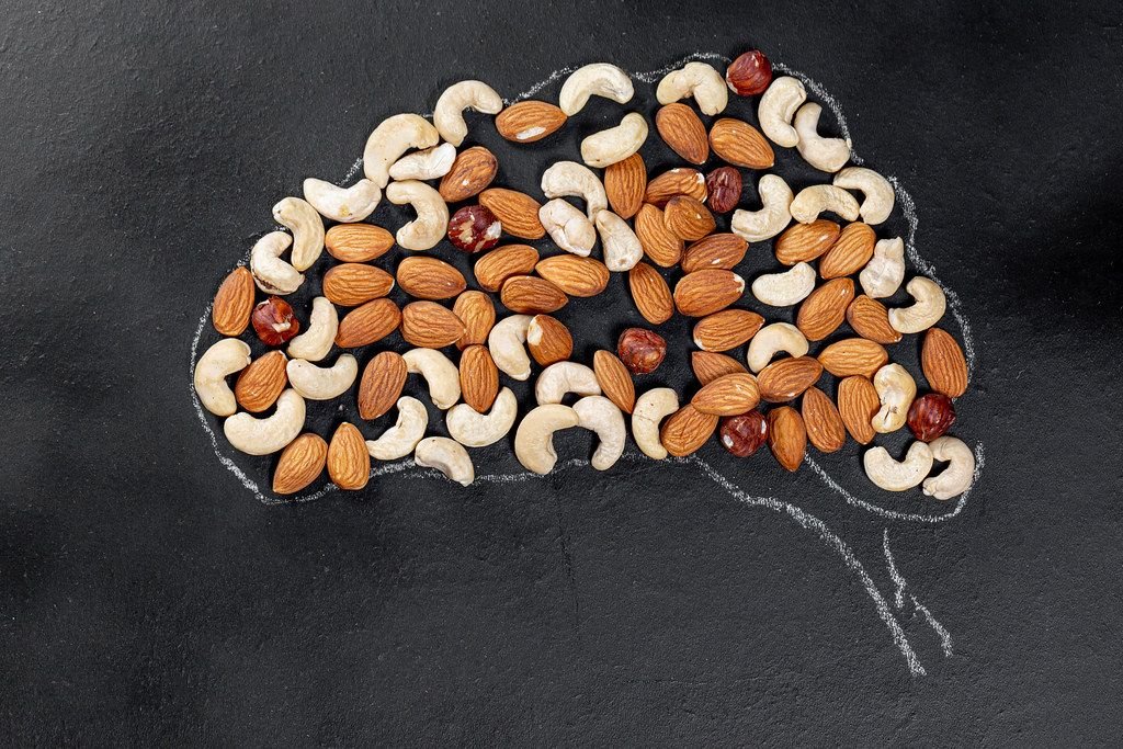 Kreidehirn auf einem schwarzen Brett mit verschiedenen Nüssen - Das Konzept der kreativen Ernährung für das Gehirn
