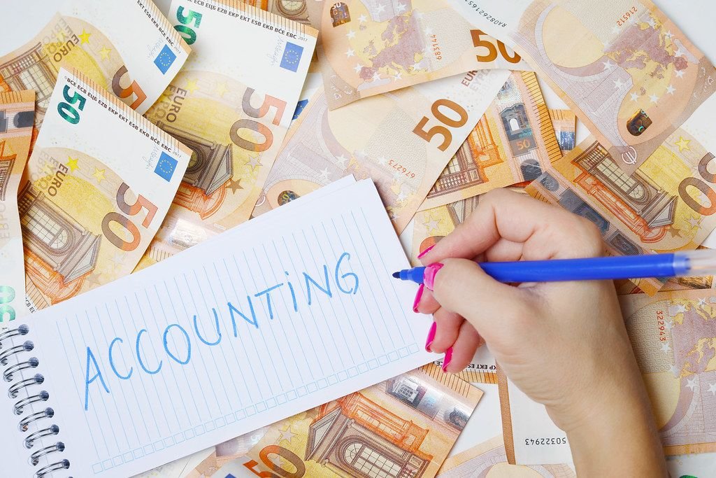 Frau schreiben "Accounting / Buchhaltung" auf einen Zettel zwischen 50-Euro-Geldscheinen