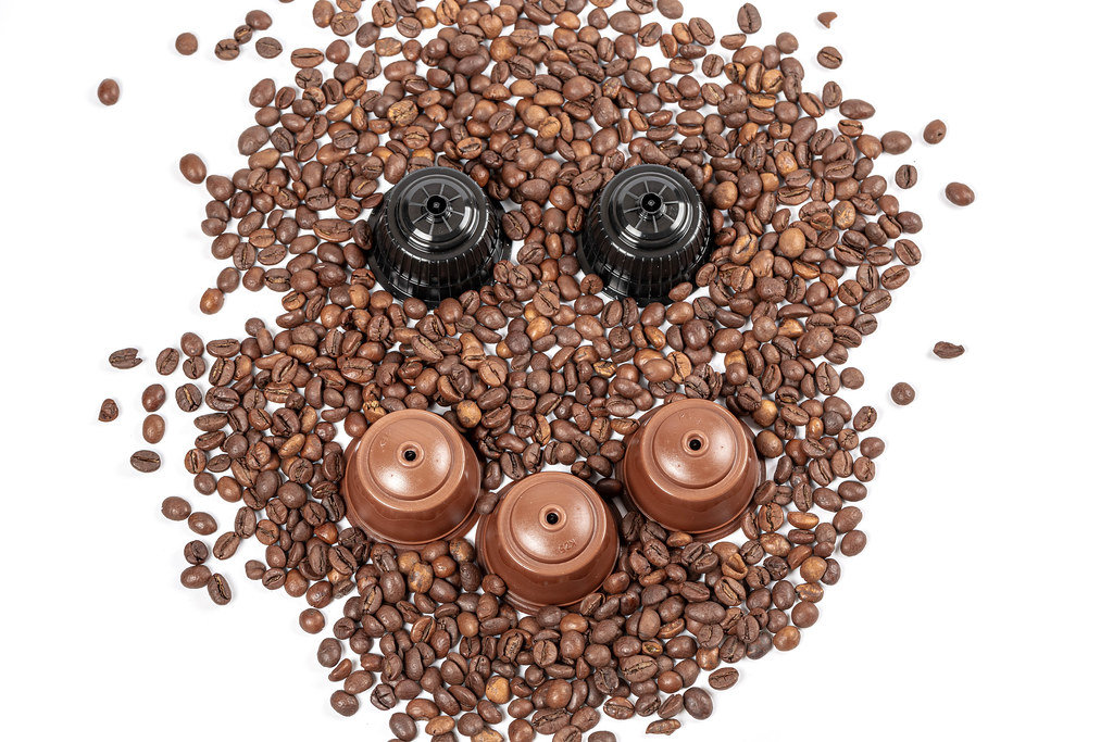 Face with a smile made from coffee beans and capsules for a coffee machine