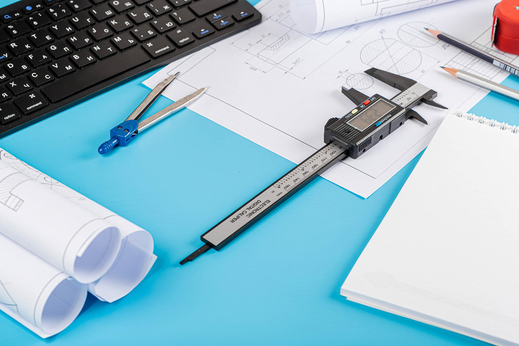 Engineer workplace concept with tools and drawings on blue background