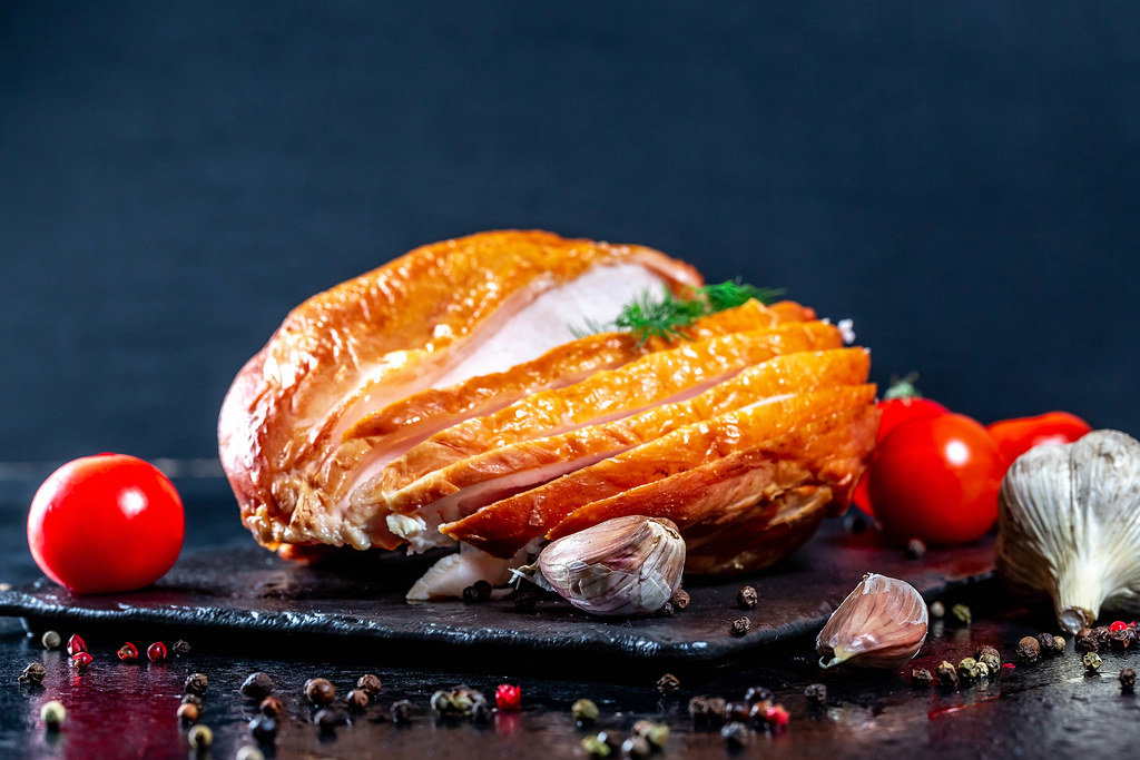 Smoked chicken breast with vegetables and spices on dark background