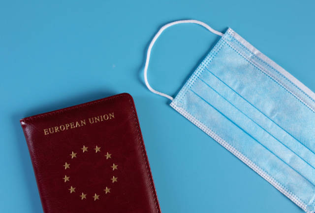 Medical face mask and passport on blue background