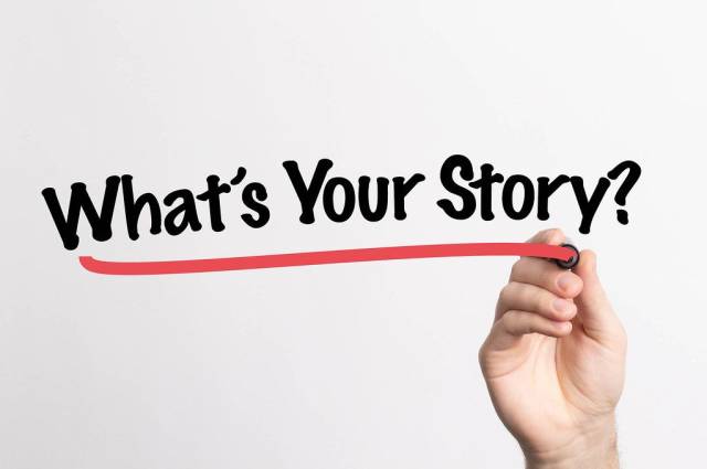 Hand schreibt "Was ist deine Geschichte?" auf ein Whiteboard