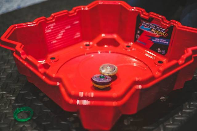 Zwei bunte Bayblade Zirkel in dafür hergestellter, roter Bayblade Burst Arena