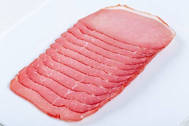 Geräucherter Schweineschinken auf einem weißen Schneidebrett