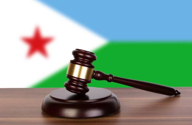 Auktionshammer / Richterhammer auf einem Holzuntergrund, vor der Flagge von Dschibuti