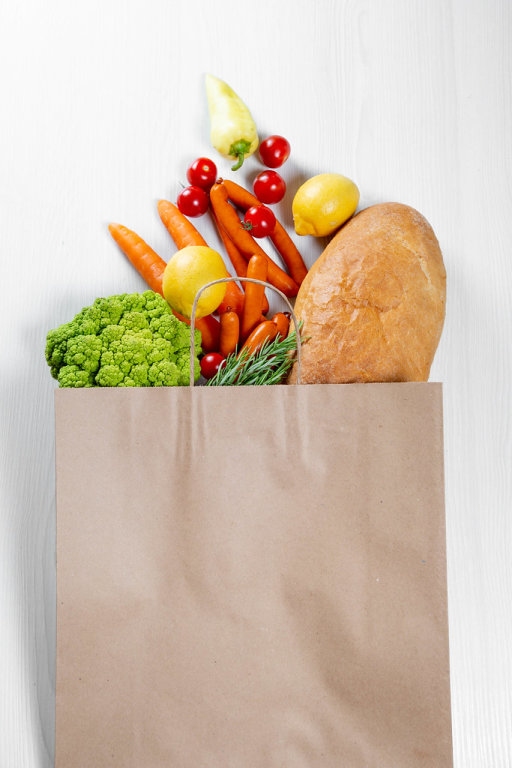 Top View Photo of Paper Bag with Fresh Vegetables and a Baguette on White Wooden Background