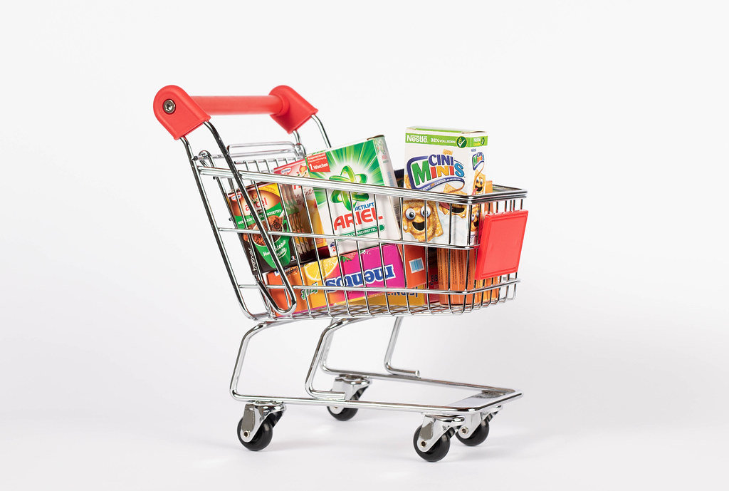 Close Up Photo of Miniature Shopping Cart full of different Groceries on White Background