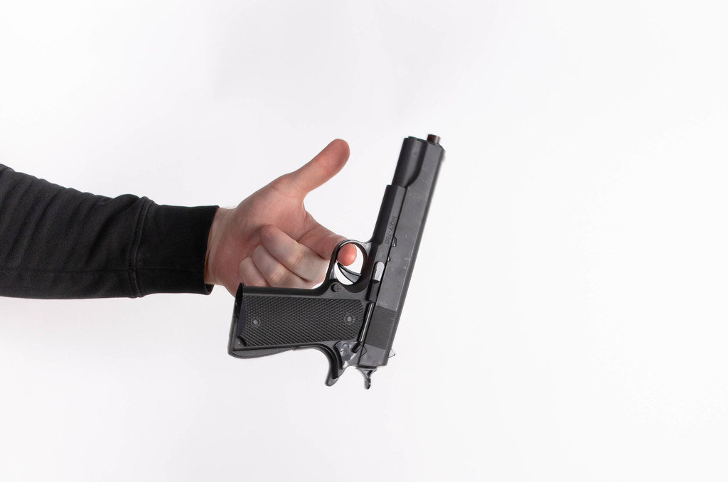 Mans hand holding gun, isolated on white