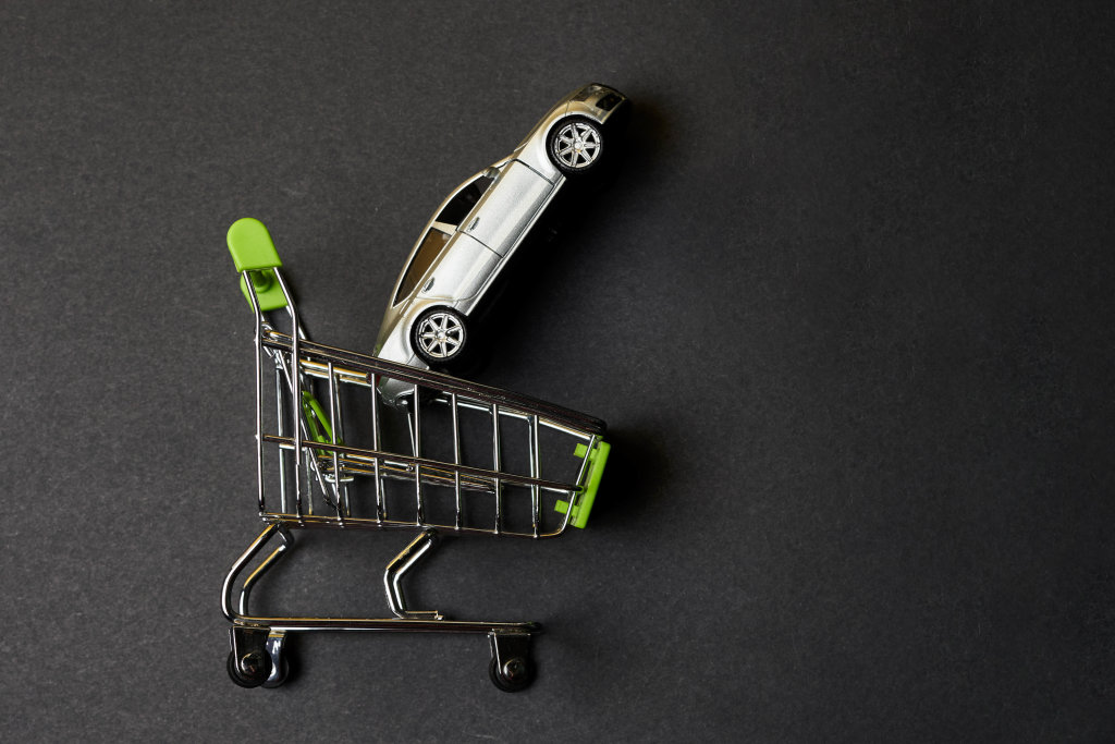 Shopping cart and toy car on dark background