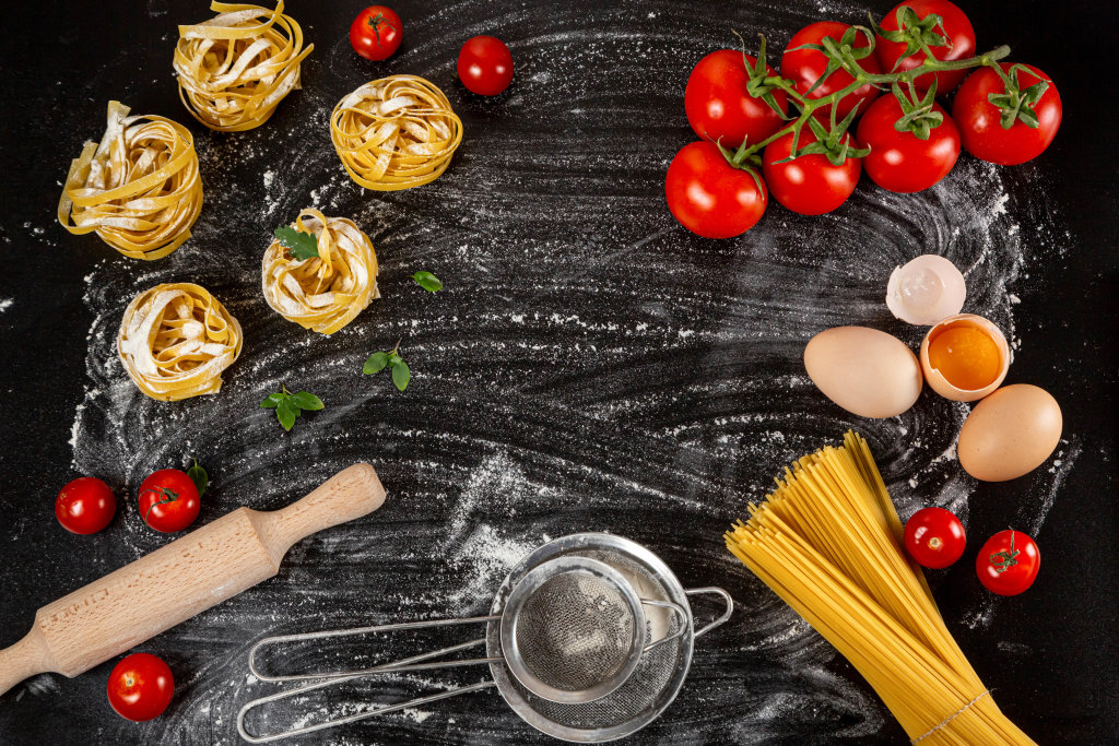 Top view, frame with Italian food products on dark background with flour