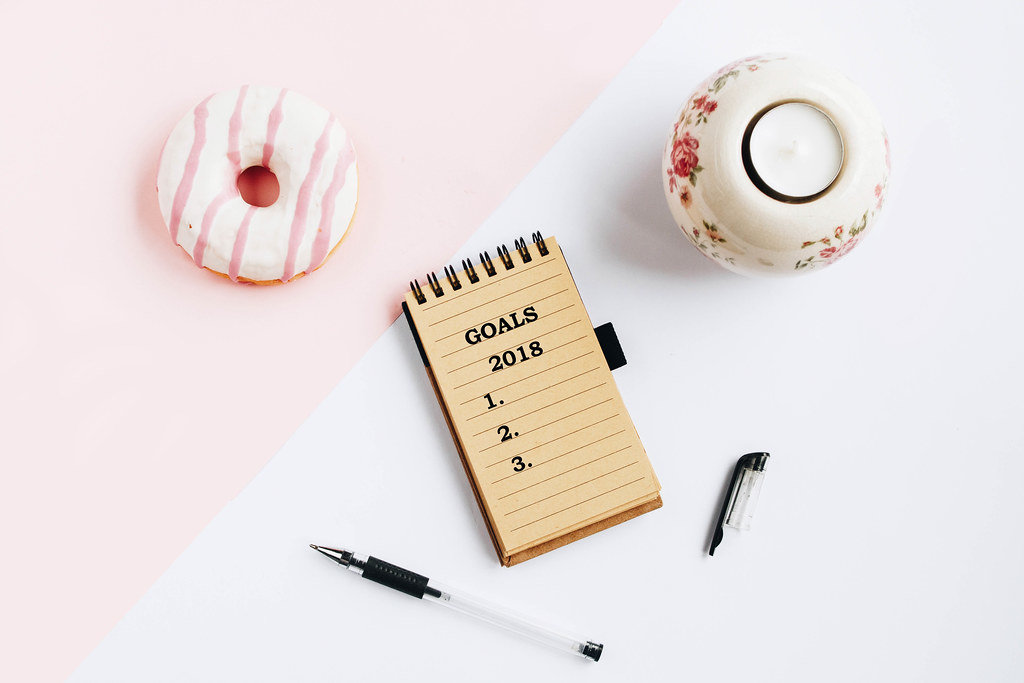 View from above on the table with a notebook and goals for 2018 year