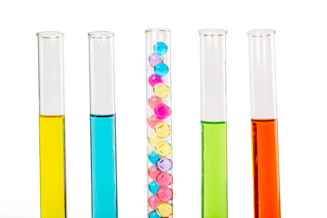 Glass test tubes with solutions of different colors and colored balls