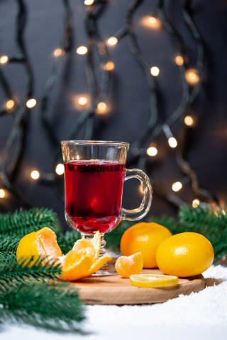 Christmas background with glass of mulled wine, tangerines, Christmas tree and garlands