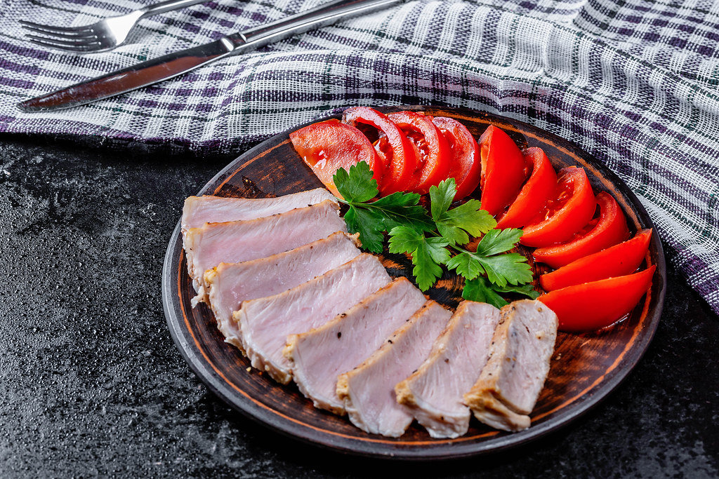 Sliced baked meat with fresh tomatoes and parsley