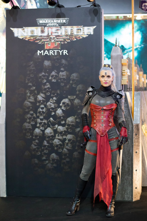 Darstellerin posiert vor dem Plakat Warhammer Inquisitor Martyr