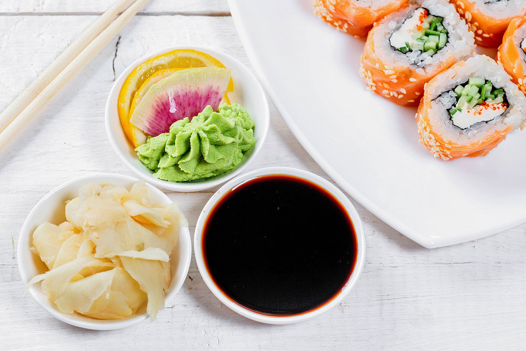 Pickled ginger, soy sauce and wasabi sauce in white saucers and sushi