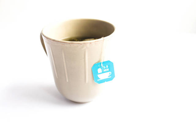 A cup of tea with a tea bag on white background