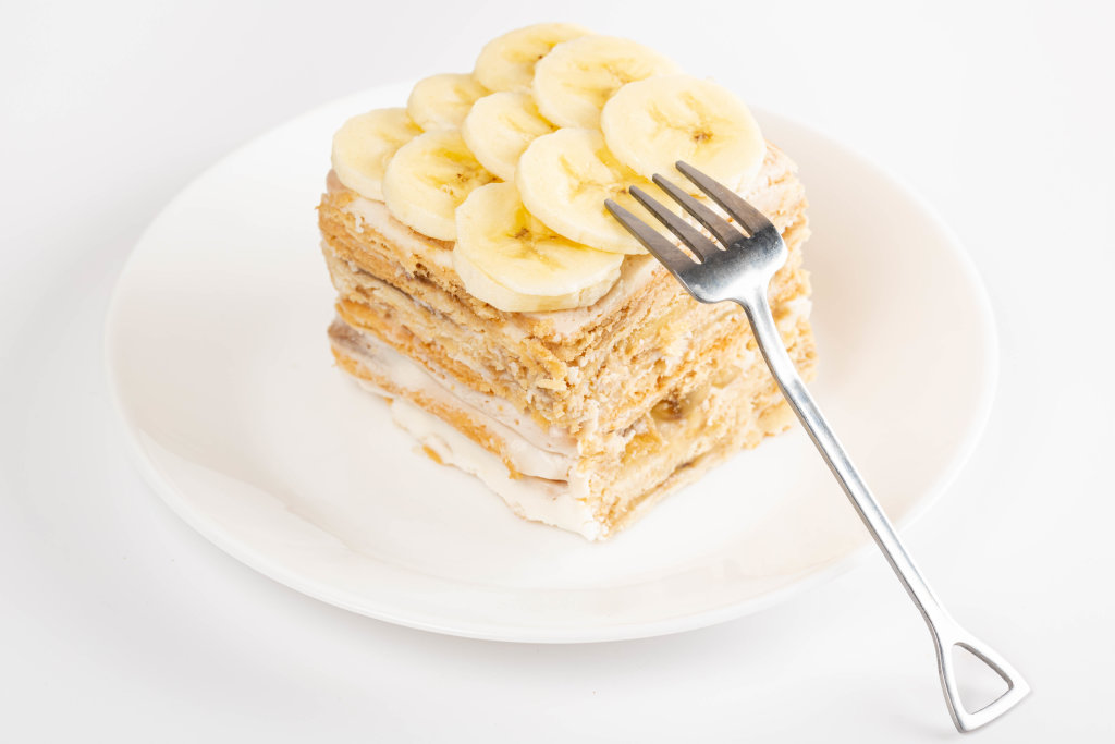 Piece of homemade cake with cream and fresh bananas