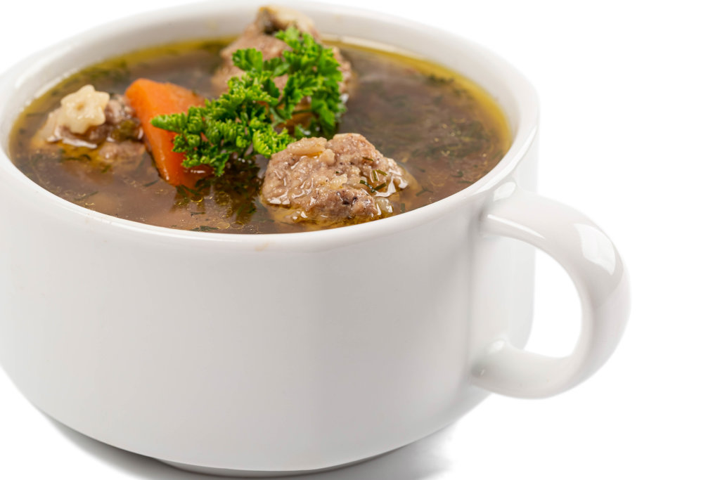 Soup with meatballs in bowl on white background