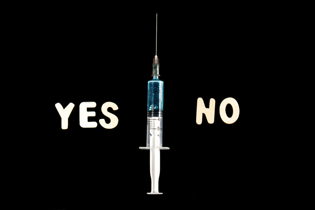 Yes and no made from wooden letters on a black background with a syringe