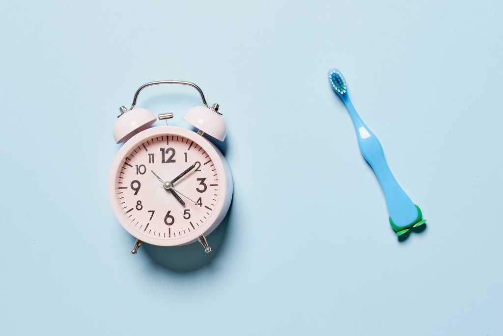 Alarm clock and toothbrush on bright blue background
