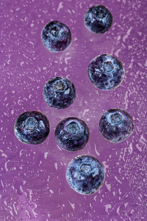 Water drops with sweet blueberry on purple background
