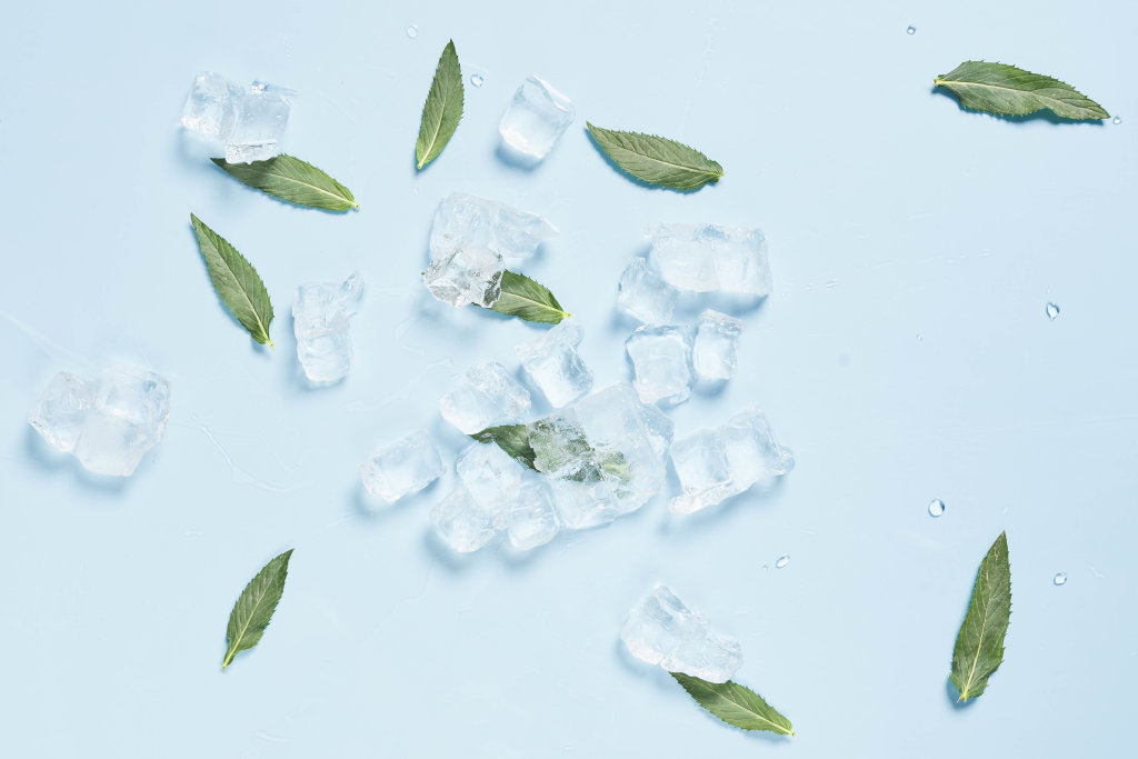 Fresh mint leaves and ice cubes on bright blue background