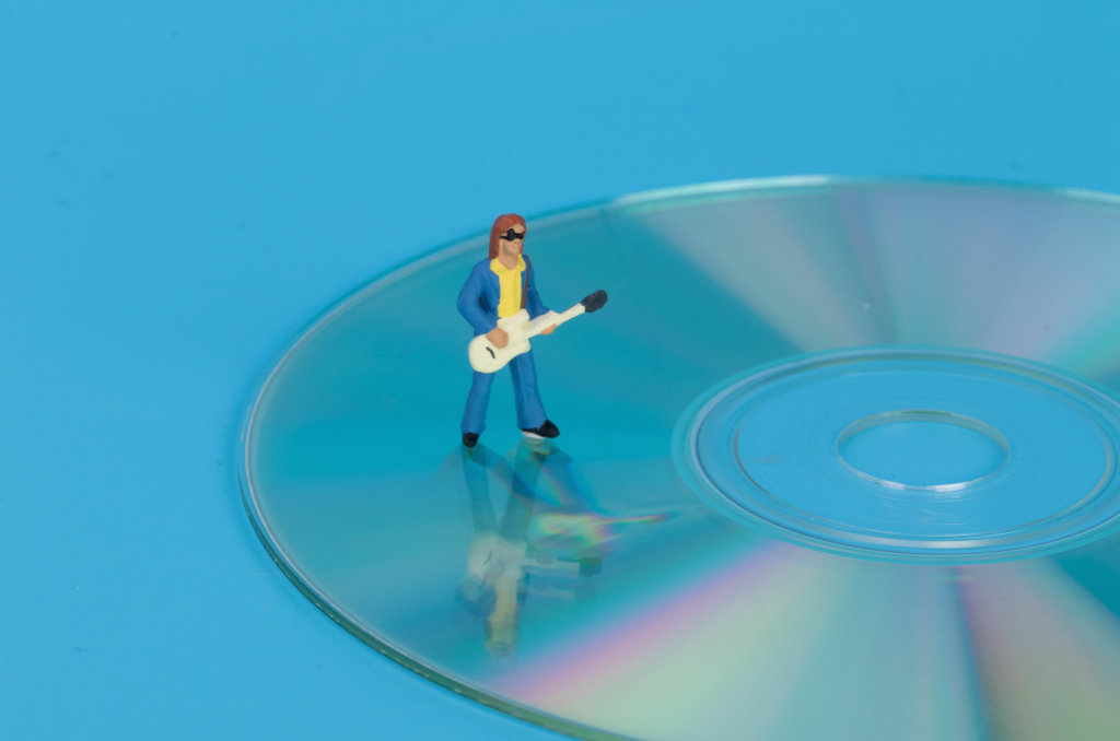 Miniature guitar player standing on CD