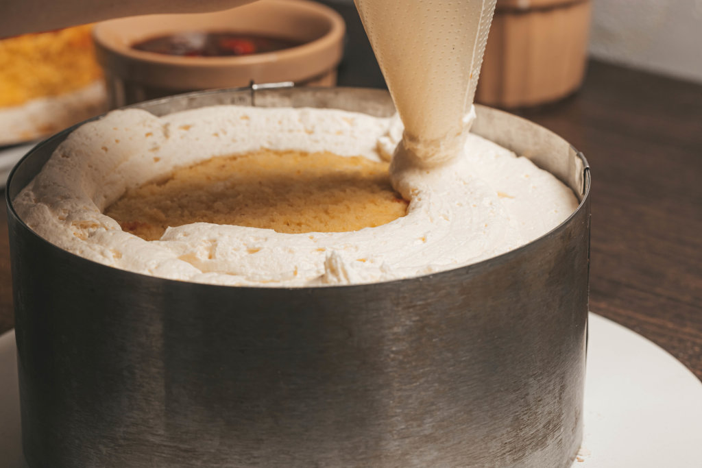 Close-up squeezing cream out of a pastry bag onto a biscuit