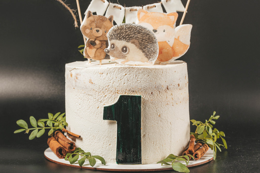 Childs birthday cake decorated with animal figurines on a dark background