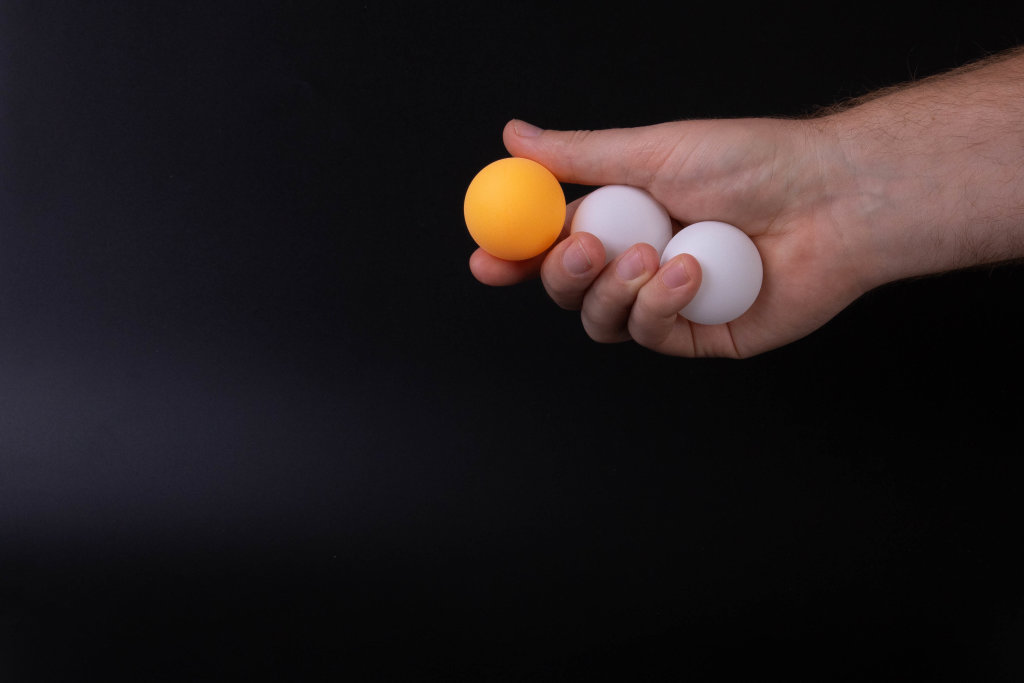 Hand holding table tennis balls on black background