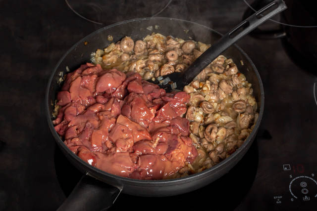Chicken liver and hearts are fried in a frying pan with onions