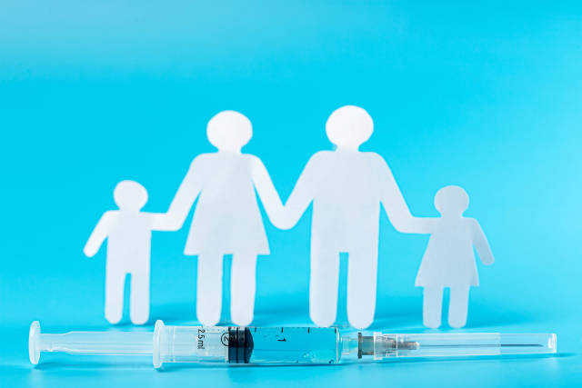 Syringe with vaccine near silhouette of family on blue background