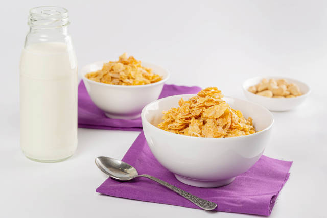 Breakfast background with two bowls of cornflakes, milk and nuts