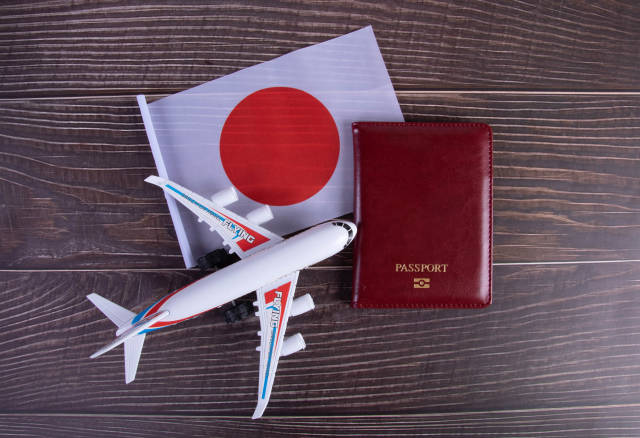 Passport, miniature airplane and flag of Japan on wooden table