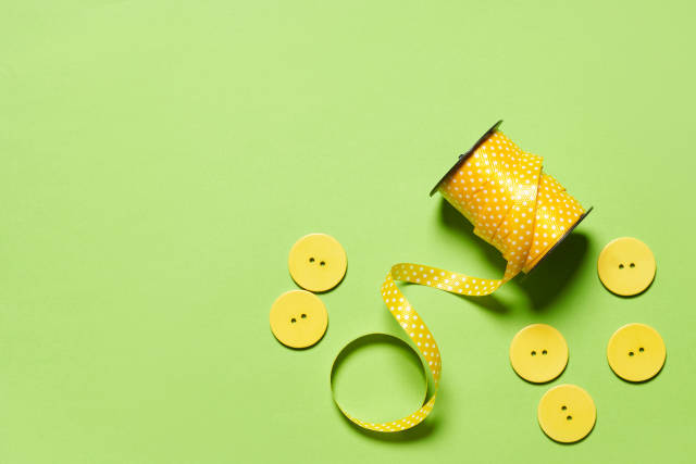 Sewing spool of thread and buttons on the green