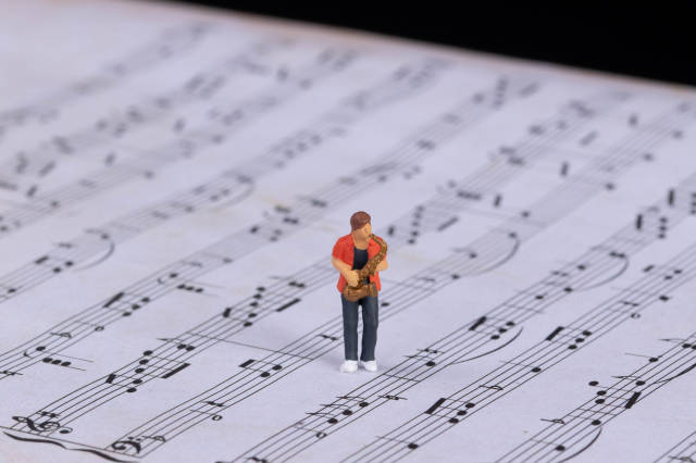 Miniature saxofonist standing on music notes