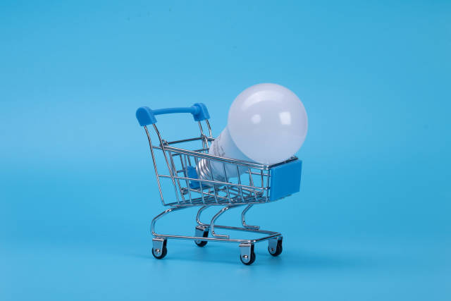 Light bulb in shopping cart on blue background
