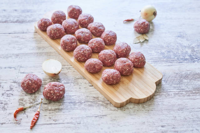 Raw meat balls on wooden cutting board