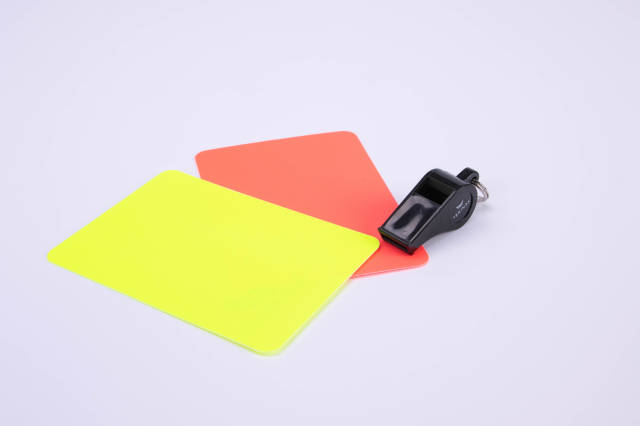 Red and yellow referee cards and a whistle for the referee on white background