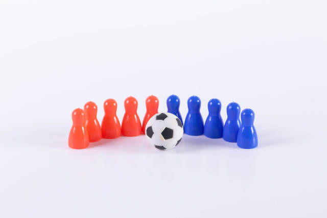 Red and blue board game pawn figures with soccer ball