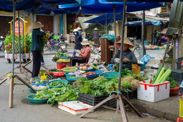 Vietnamese Women selling Herbs, Fruits and Vegetables at a Street Market at the Entrance of the Walking Street in Hoi An, Vietnam