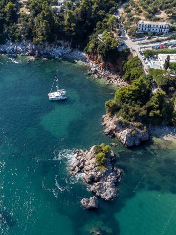 Ein Segelboot im türkisblauen Meer Stafylos auf Skopelos: Drohnenaufnahme von der Felsküste