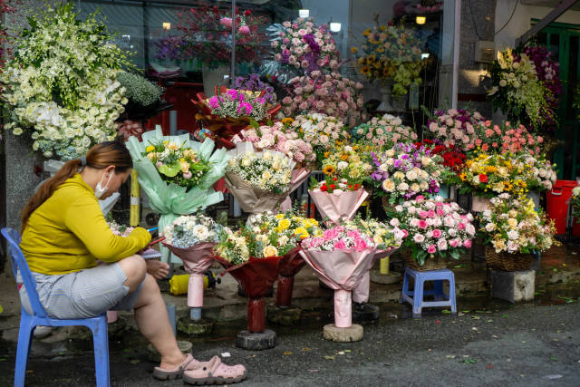 Vietnamese Woman selling colorful Flower Bouquets with Roses, Sunflowers and other kinds of Flowers at the Ho Thi Ky Street Flower Market in Ho Chi Minh City, Vietnam