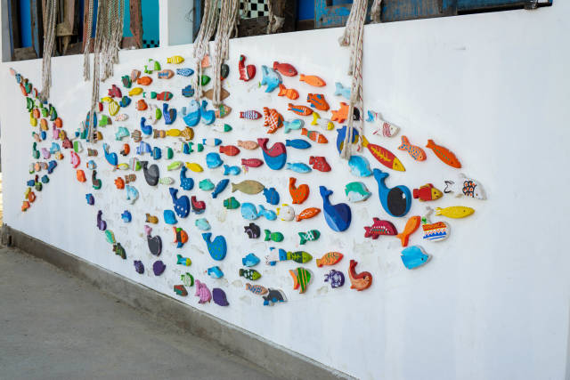 Großer Fisch als Kunstwerk an einer Hauswand mit vielen kleinen bunten Fischen und Walen an einem öffentlichen Strand in Da Nang, Vietnam