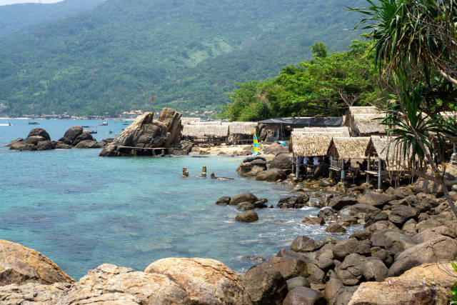 Restaurant und Beach Bar mit Strohhütten an einem Strand mit großen Steinen und Felsen auf der Son Tra Halbinsel in Da Nang, Vietnam