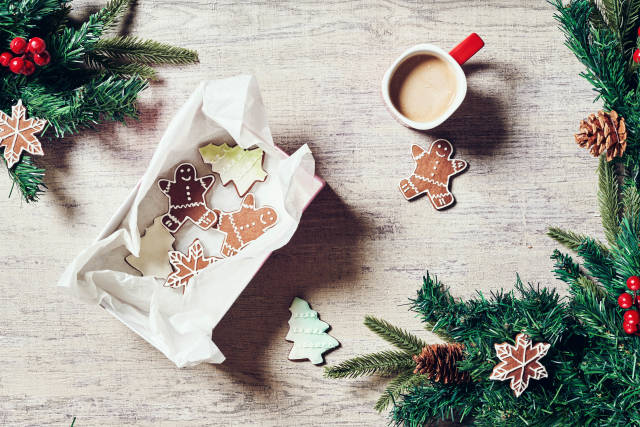 Cozy Christmas background with coffee cup, baked cookies and pine cones on wooden background